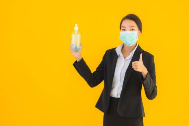 Güzel bir iş kadını portresi. Maske takıyor. Korunmak için alkol jeli kullanıyor.
