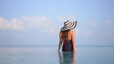 Güzel Asyalı bir kadının, tatil için otel tatil beldesinde yüzme havuzunda dinlendiği görüntüler.