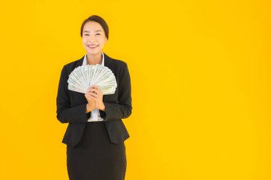 Sarıya boyanmış arka planda bir sürü nakit parası olan güzel bir Asyalı kadın portresi.