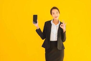 Portre güzel genç Asyalı kadın akıllı cep telefonu ve kahve fincanı ile izole edilmiş sarı arka planda