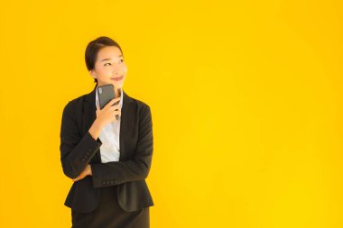 Portre güzel genç Asyalı kadın akıllı cep telefonu ve kahve fincanı ile izole edilmiş sarı arka planda