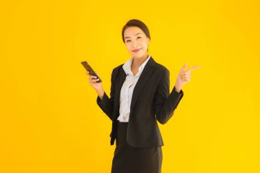 Portre güzel genç Asyalı kadın akıllı cep telefonu ve kahve fincanı ile izole edilmiş sarı arka planda