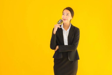 Sarı izole edilmiş arka planda kredi kartı olan güzel, genç Asyalı kadın portresi.