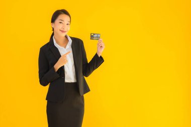 Sarı izole edilmiş arka planda kredi kartı olan güzel, genç Asyalı kadın portresi.