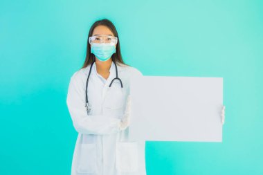 Mavi izole edilmiş arka planda boş ilan panosuyla güzel Asyalı doktor kadın portresi.