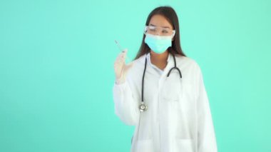 Turkuazda izole edilmiş şırıngalı güzel Asyalı kadın doktorun görüntüleri.