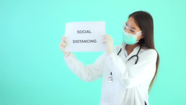 美丽的亚洲女医生拿着用绿松石隔开的带有社会距离题词的文件的镜头 — 图库视频影像