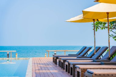 Otel tatil beldesinde açık havuz etrafında güzel boş sandalye şemsiyesi.