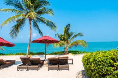 Güzel tropikal deniz okyanusu, şemsiyesi ve sandalyesi ile mavi gökyüzünde hindistan cevizi palmiyesinin etrafında tatil için