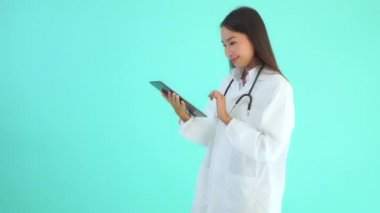 Turkuazda izole edilmiş dijital tabletli güzel Asyalı kadın doktorun görüntüleri.