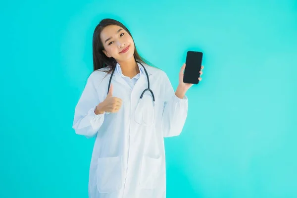 在蓝色隔离背景下 亚洲年轻貌美的女医生用手机在诊所或医院看病 — 图库照片