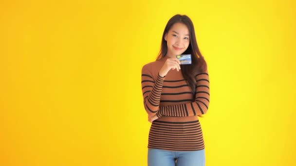一个漂亮的亚洲女人带着信用卡被黄色隔离的镜头 — 图库视频影像