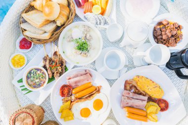 Kızarmış yumurta omletli, jambonlu, meyveli, sütlü kahveli ve yüzme havuzlu bir tepside yüzen kahvaltı.