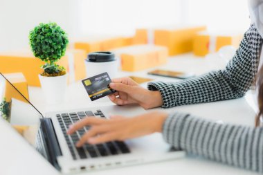 Güzel bir Asyalı kadının portresi online alışveriş malzemesi olarak dizüstü bilgisayarla kredi kartı kullanıyor.