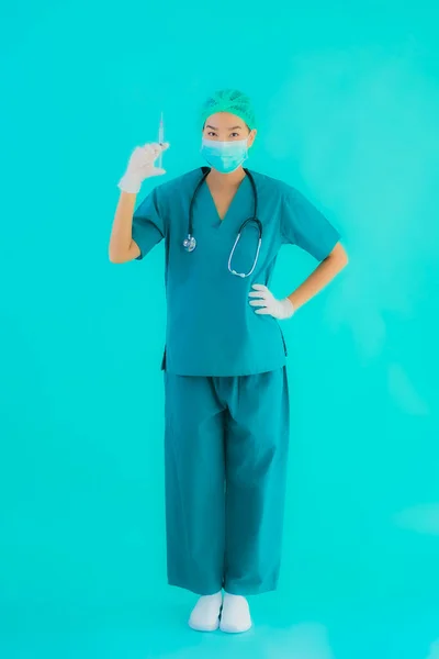 Portrait beautiful young asian doctor woman wear mask with syringe vaccine for protect from covid19 or coronavirus on blue isolated background