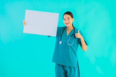 Fotokopi için boş kâğıt tahtası olan güzel Asyalı genç doktor kadın hastane ve klinikteki sağlık hizmetleri konseptinde mavi izole edilmiş arka plan.