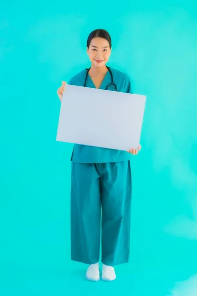 青い隔離された背景にコピースペースのための空の紙板紙と肖像画の美しい若いアジアの医師の女性 病院やクリニックのコンセプトのヘルスケア — ストック写真