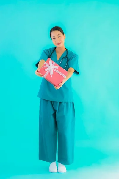 肖像美しい若いアジアの医師の女性ショー赤ギフトボックス上の青隔離された背景 — ストック写真