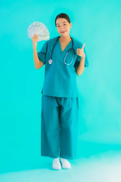 肖像美しい若いアジアの医師の女性ショーお金と現金オン青隔離された背景 — ストック写真