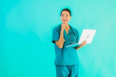 Mavi izole arka planda dizüstü bilgisayarı olan güzel Asyalı doktor kadın portresi.