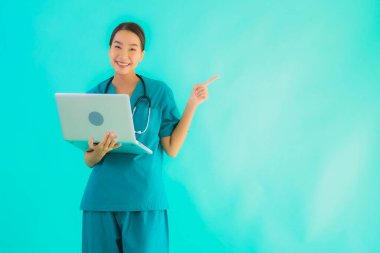 Mavi izole arka planda dizüstü bilgisayarı olan güzel Asyalı doktor kadın portresi.