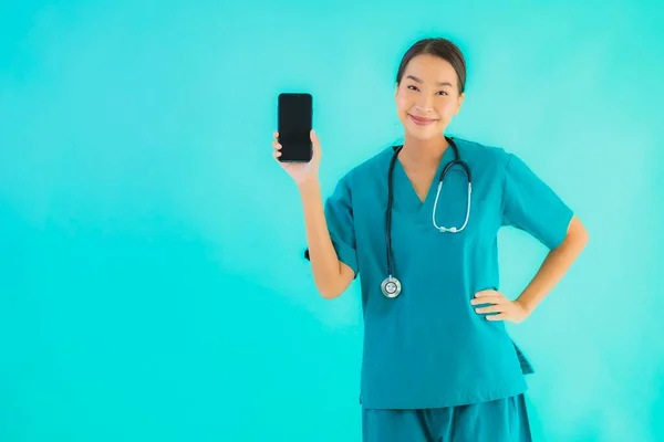 年轻美丽的亚裔女医生在蓝色孤立的背景下展示出聪明的手机 — 图库照片