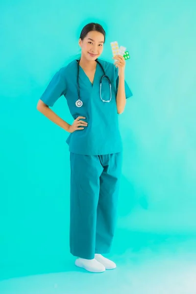 肖像画美しいです若いですアジアの医師女性とともに丸薬や薬上の青隔離された背景 — ストック写真