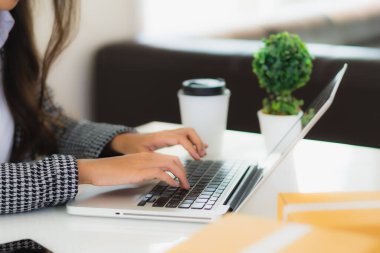 Güzel Asyalı iş kadını portresi evden bilgisayarlı cep telefonuyla karton kutuyla çevrimiçi alışveriş için hazır bekliyor.