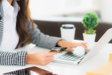 Güzel bir Asyalı kadının portresi online alışveriş malzemesi olarak dizüstü bilgisayarla kredi kartı kullanıyor.