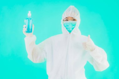 Güzel bir portre genç Asyalı doktor. Özel süit ve maske takıyor. Alkol jeli ve mavi izole bir arka plan.