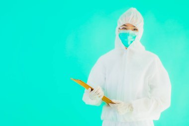 Güzel, genç Asyalı doktor kadın koronavirüsten korunmak için ppe ya da kişisel koruyucu ekipman takıyor ya da mavi izole arka planda beyaz kartı olan 19. bölgede yaşıyor.