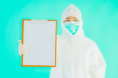 Güzel, genç Asyalı doktor kadın koronavirüsten korunmak için ppe ya da kişisel koruyucu ekipman takıyor ya da mavi izole arka planda beyaz kartı olan 19. bölgede yaşıyor.