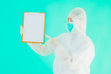Güzel, genç Asyalı doktor kadın koronavirüsten korunmak için ppe ya da kişisel koruyucu ekipman takıyor ya da mavi izole arka planda beyaz kartı olan 19. bölgede yaşıyor.