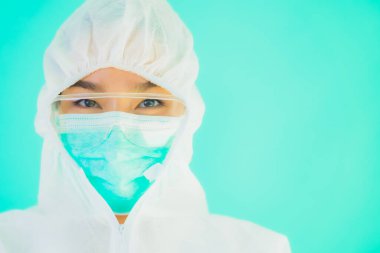 Güzel, genç Asyalı doktor kadın portre. Koronavirüsten ya da mavi arka planda kovid19 'dan korunmak için ppe ya da kişisel koruyucu ekipman takıyor.
