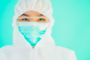 Güzel, genç Asyalı doktor kadın portre. Koronavirüsten ya da mavi arka planda kovid19 'dan korunmak için ppe ya da kişisel koruyucu ekipman takıyor.