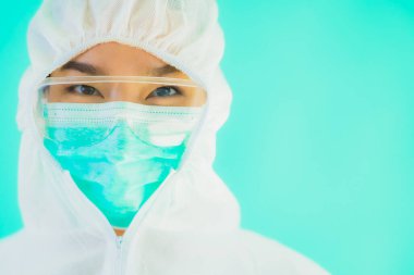 Güzel, genç Asyalı doktor kadın portre. Koronavirüsten ya da mavi arka planda kovid19 'dan korunmak için ppe ya da kişisel koruyucu ekipman takıyor.
