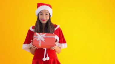 Sarı renkli kırmızı hediye kutusu olan Noel Baba kostümlü güzel bir Asyalı kadın görüntüsü.