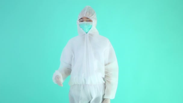 トルコ石に隔離された空白の空間を指差す防護服や仮面を着たアジア系女性の映像 — ストック動画
