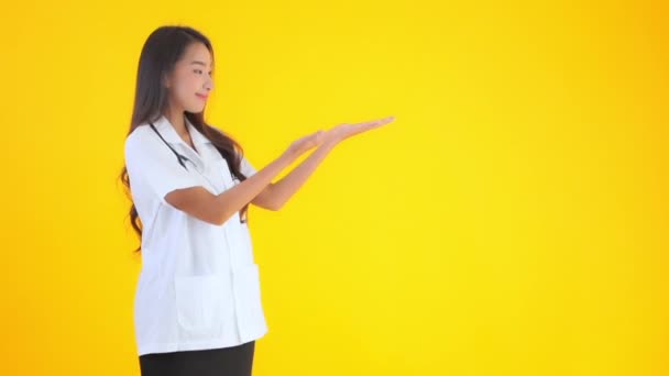 美丽的亚洲医生妇女指着用黄色隔开的空白空间的镜头 — 图库视频影像