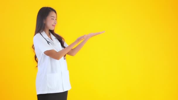 Metraje Hermosa Asiática Médico Mujer Apuntando Blanco Espacio Aislado Amarillo — Vídeo de stock