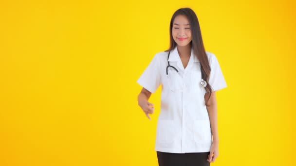 黄色に隔離された電話のジェスチャーを示す美しいアジアの医師の女性の映像 — ストック動画