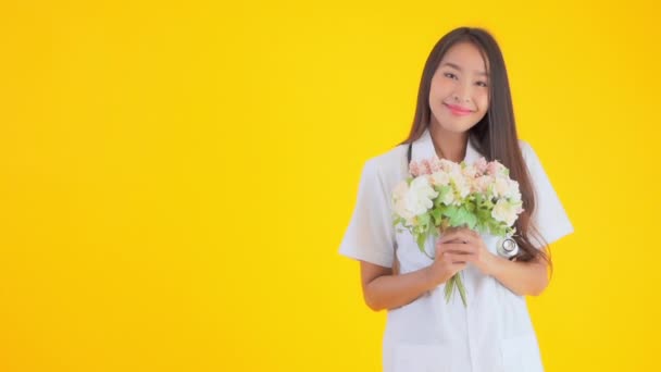 美丽的亚洲医生女人拿着一束黄色的花的镜头 — 图库视频影像