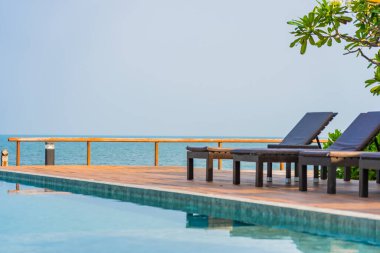 Otel tatil beldesinde açık havuz etrafında güzel boş sandalye şemsiyesi.