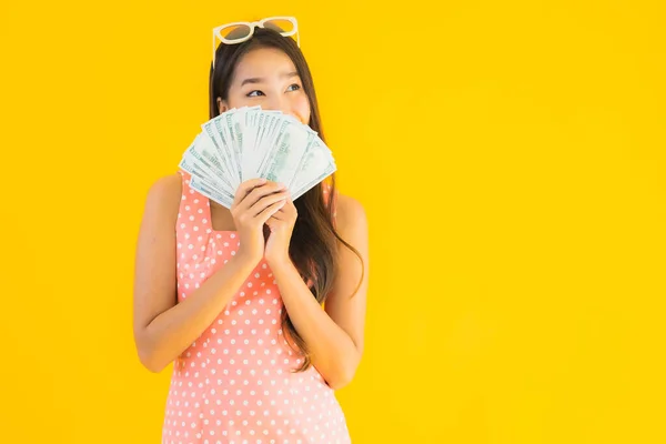 亚洲年轻貌美的女性形象 有很多现金和金钱 背景是黄褐色孤立的 — 图库照片