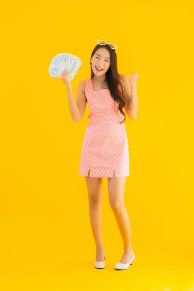 在黄色孤立的背景下 亚洲年轻貌美的女性展现出了大量的现金和金钱 — 图库照片