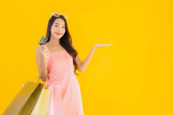 노란색외진 배경에 쇼핑백 스마트폰 신용카드가 아름다운 아시아 여성의 — 스톡 사진