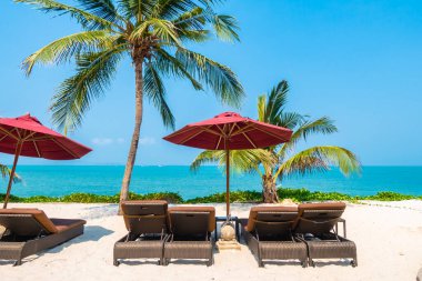 Güzel tropikal deniz okyanusu, şemsiyesi ve sandalyesi ile mavi gökyüzünde hindistan cevizi palmiyesinin etrafında tatil için