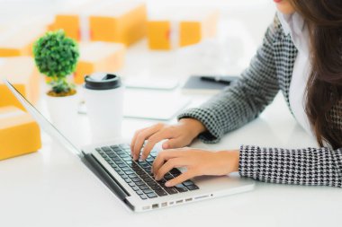 Güzel Asyalı iş kadını portresi evden bilgisayarlı cep telefonuyla karton kutuyla çevrimiçi alışveriş için hazır bekliyor.