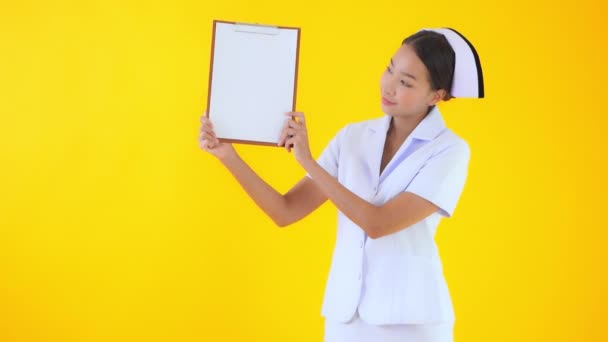 美しいアジアの女性の映像は黄色に隔離された白いクリップボードを保持 — ストック動画