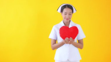 Sarıda kırmızı kalp taşıyan güzel bir Asyalı hemşire görüntüsü.